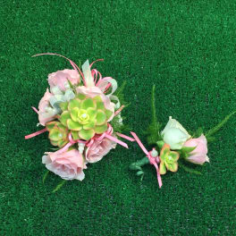 Pink floral corsage and boutonniere with succulents on green turf