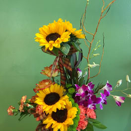Tall mixed bouquet with sunflowers, orchids, and roses in a black container