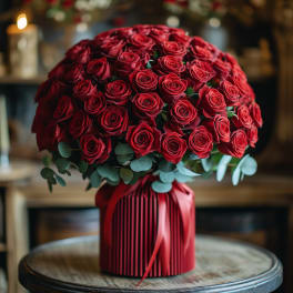 Round bouquet of red roses with eucalyptus in a red wrapped base