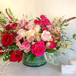 Large bouquet of pink and red roses in a green glass vase