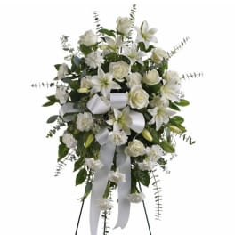 White floral standing spray with lilies, roses, and ribbon