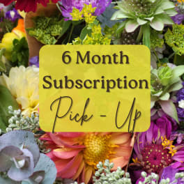 Colorful mixed flowers behind a sign reading 6 Month Subscription Pick-Up