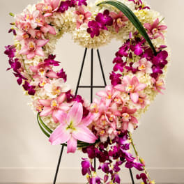 Heart-shaped floral wreath with pink and purple orchids on a stand