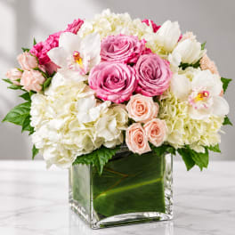 Pink and white flower arrangement in a square glass vase