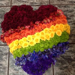 Heart-shaped floral arrangement in rainbow colors on a tiled floor