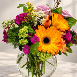 Mixed bouquet with orange gerbera daisies and pink roses in a glass vase