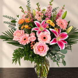 Pink and white mixed flower arrangement in a clear glass vase