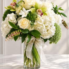 White and cream bouquet in a clear glass vase with a ribbon