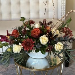 Mixed roses and burgundy flowers arranged in a white vase