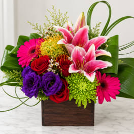 Colorful bouquet with lilies, roses, gerbera daisies, and chrysanthemums in a wooden box