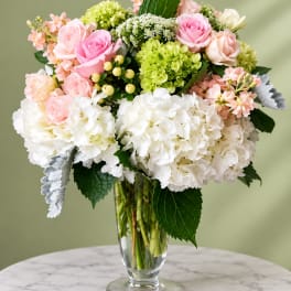 Pink and white roses with hydrangeas in a clear glass vase