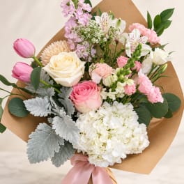 Pink and white mixed bouquet wrapped in brown paper with a pink ribbon