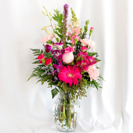 Mixed pink and purple flower arrangement in a clear glass vase