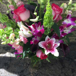 Bouquet of pink lilies, roses, and orchids in a glass vase
