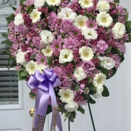 Heart-shaped pink and white floral standing spray with a purple ribbon