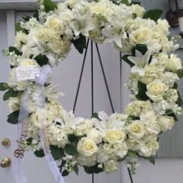 White floral wreath with roses and lilies on a stand