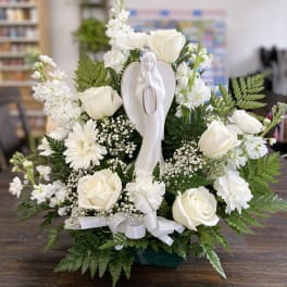 White roses and daisies arranged around a praying angel figurine