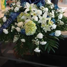 Large white and blue floral funeral spray with lilies and hydrangeas