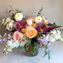 Mixed bouquet of roses, orchids, and white blooms in a glass vase