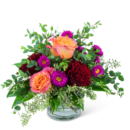 Peach and burgundy roses with purple daisies in a glass vase