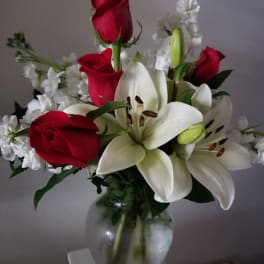 Red roses and white lilies arranged in a glass vase