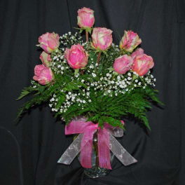 Pink roses in a glass vase with baby's breath and a pink ribbon