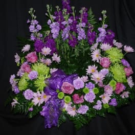 Purple and pink floral wreath with a ribbon on a dark background