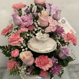 Pink and lavender floral arrangement in a white vase with butterfly accents