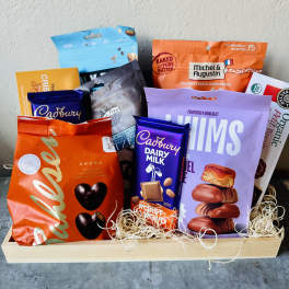 Assorted candy and cookie gift basket in a wooden tray