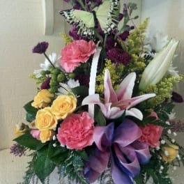 Colorful floral arrangement with a butterfly and purple ribbon
