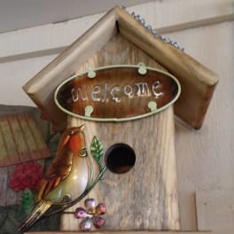 Wooden birdhouse with a decorative bird and "welcome" sign