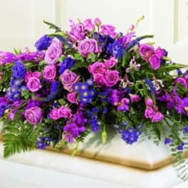 Large purple and pink floral arrangement on a casket