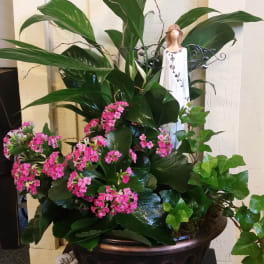 Potted green plant with pink flowers and a small angel figurine