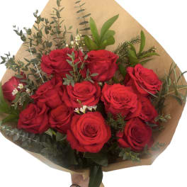 Bouquet of red roses with greenery wrapped in brown paper