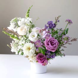 Purple and white mixed bouquet in a white vase