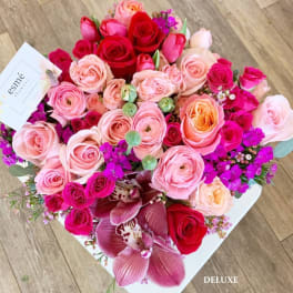 Bouquet of pink and red roses with purple orchids in a white box