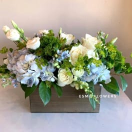 Cream roses and blue hydrangeas in a wooden box