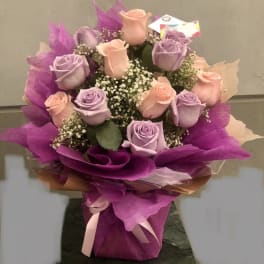 Bouquet of lavender and peach roses wrapped in purple paper
