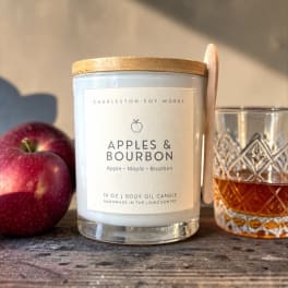 Apple-scented candle with a glass and two apples beside it