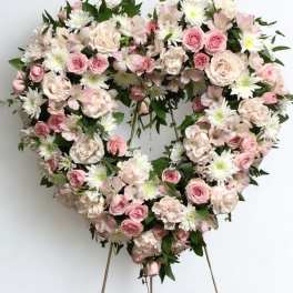 Heart-shaped floral wreath with pink and white flowers on a stand