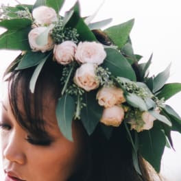 Woman wearing a floral crown of pale pink roses and greenery