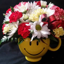 Bouquet of red and white flowers in a yellow smiley-face mug