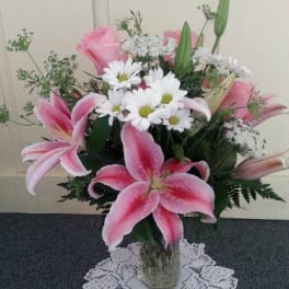 Pink lilies and white daisies arranged in a glass vase