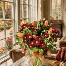 Bouquet of burgundy daisies and peach tulips in a glass vase