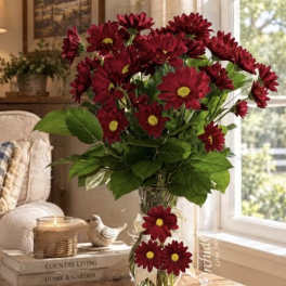 Red daisy bouquet in a clear glass vase on a table