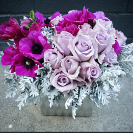 Lavender roses and magenta anemones in a square vase