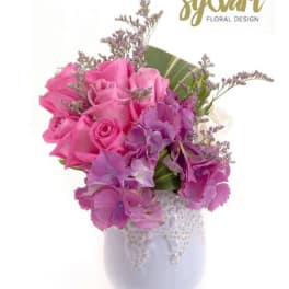 Pink roses and purple flowers arranged in a white vase