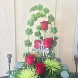 Tall arrangement of red roses with green foliage around a silver stand