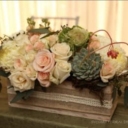 Low floral arrangement with pale roses and succulents in a rustic box