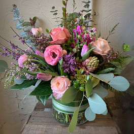 Pink and peach roses with purple blooms in a glass vase